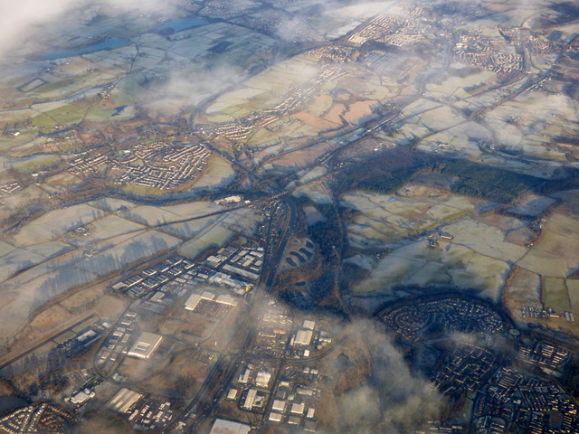 Castlecary from the air. The canal crosses the picture bottom left to top right (west to east). The railway is just below it with the white roof of the CMS buildings at Castlecary between them. The Red Burn (SUDS) ponds can be seen south of the Arches which are just visible. Cumbernauld's Wardpark can be seen being divided by the M80 as it heads north towards Stirling. At the bottom left the edge of Westerwood can be seen below Cumbernauld Airport. At the bottom, the small white T-shaped building is the Old Inns petrol station which separates Castlecary Road from the M80. The curve of Forest Road round Whitelees in Cumbernauld and Whitelees Roundabout which divides it from Abronhill are at the bottom right. North of Castlecary, Banknock can be seen on the left extending towards Longcroft and Dennyloanhead with Denny and Bonnybridge at the top right.