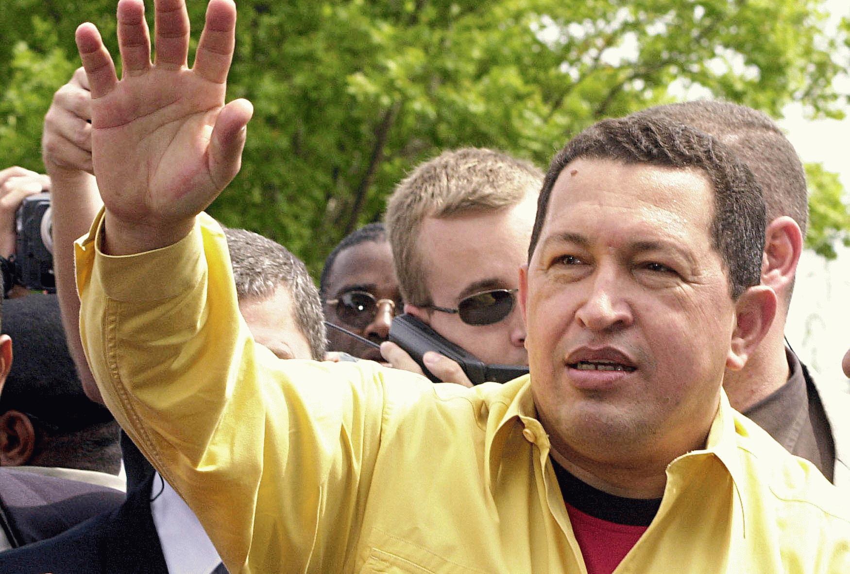 Hugo Chávez, de camisa amarela, saudando a multidão, com vários seguranças