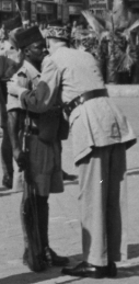 Foto de um soldado negro em posição de sentido, um general, por trás, dando-lhe um abraço.