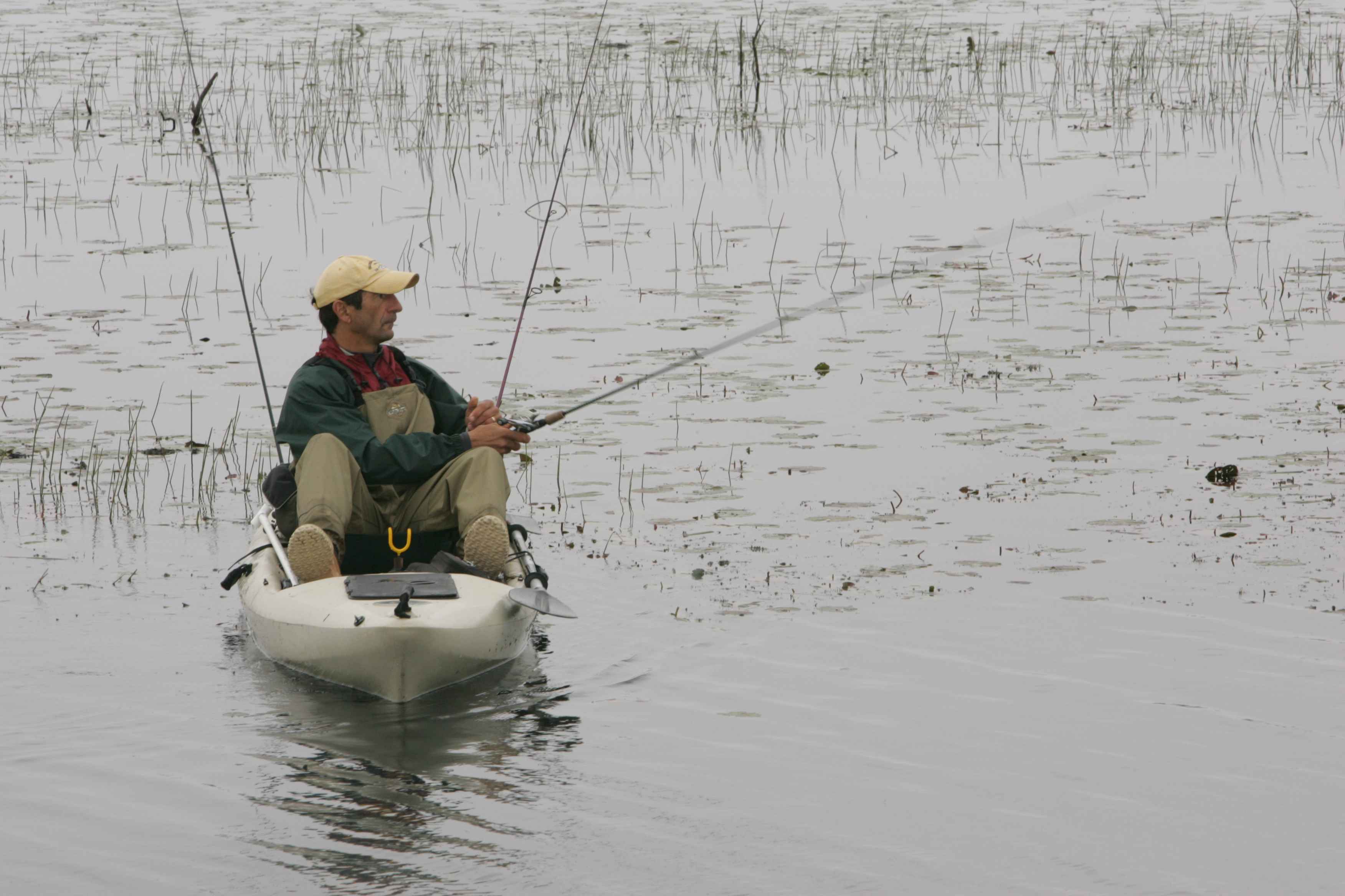 File:Man in white canoe casting fishing line into water.jpg - Wikimedia  Commons