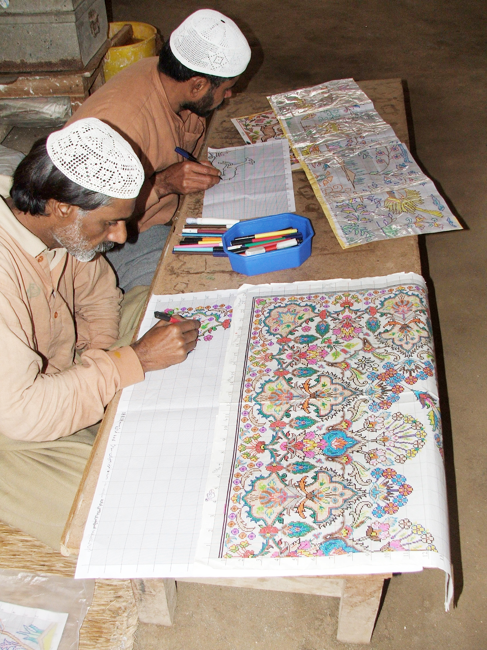 https://upload.wikimedia.org/wikipedia/commons/5/5d/Correctional_Activities_at_Central_Jail_Faisalabad%2C_Pakistan_in_2010_-_Convict_artists_busy_in_drawing_designs_of_carpets_on_graph_papers.JPG