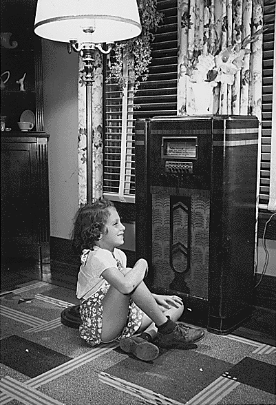 Girl listening to vacuum tube console radio in the 1940s. During the golden age of radio, 1925–1955, families gathered to listen to the home radio receiver in the evening