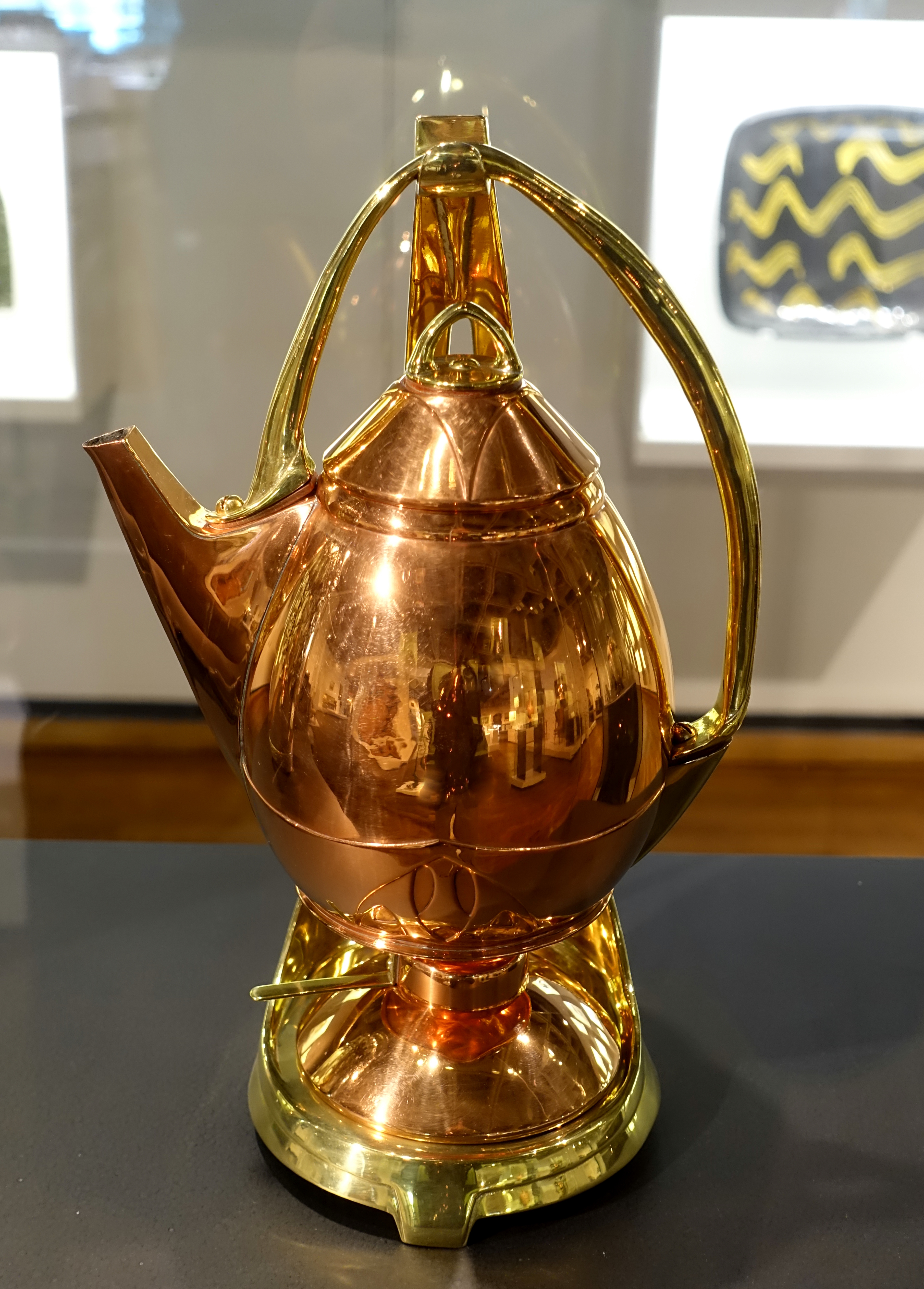 https://upload.wikimedia.org/wikipedia/commons/6/66/Tea_kettle_and_stand%2C_Albin_Mueller%2C_made_by_Eduard_Hueck_Metallwarenfabrik%2C_Luedenscheid%2C_Germany%2C_c._1903%2C_copper%2C_brass_-_Montreal_Museum_of_Fine_Arts_-_Montreal%2C_Canada_-_DSC09281.jpg