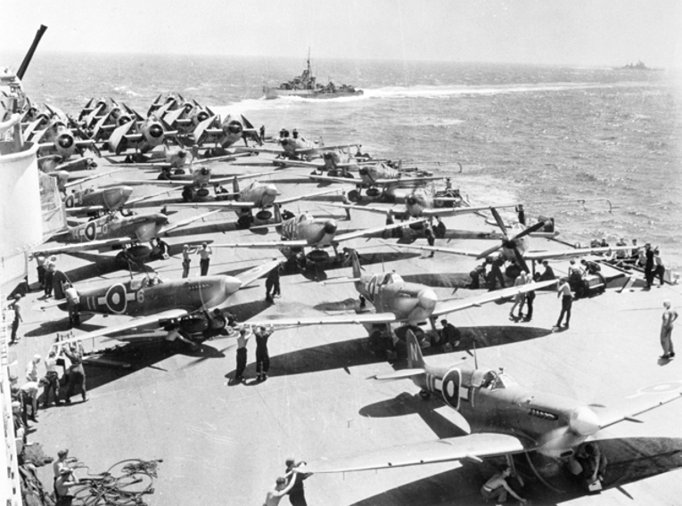 Royal Navy Fleet Air Arm Avengers, Seafires and Fireflies on HMS Implacable warm up their engines before taking off.