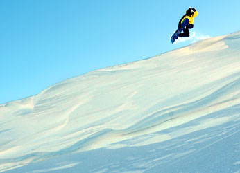 Snowboarder drops off a cornice.