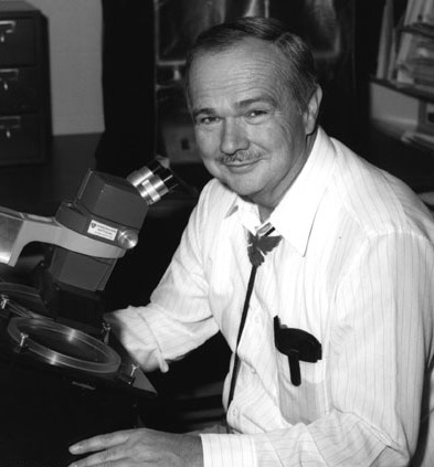 Eugene Shoemaker (1928-1997), pioner en la investigació dels cràter d'impacte, aquí amb un microscopi cristal·logràfic que s'utilitza per examinar els meteorits