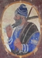 Fresco of a Sikh warrior wearing blue clothes and turban with weapons in hands. Possibly a depiction of either Bota Singh or Garja Singh. Located at Khem Singh Bedi's haveli, ca.1850-1890 Fresco of a Sikh warrior wearing blue clothes and turban with weapons in hands.jpg