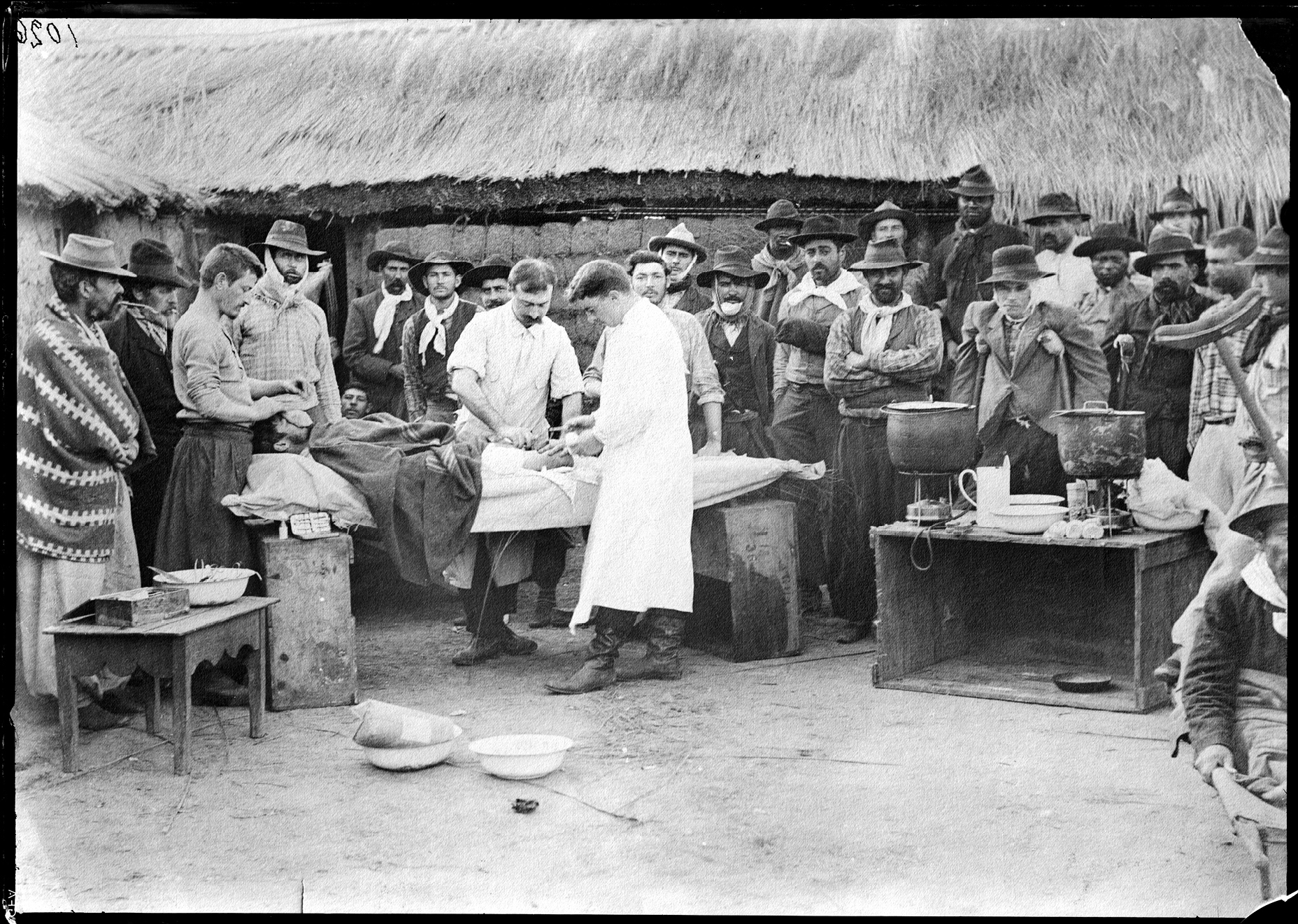 Intervención quirúrgica al aire libre llevada a cabo en el Hospital Nacionalista por los cirujanos miembros de la guardia médica de Aparicio Saravia: Baldomero Cuencas y Lamas y Bernardino Fonticiolla, durante la revolución de 1897.