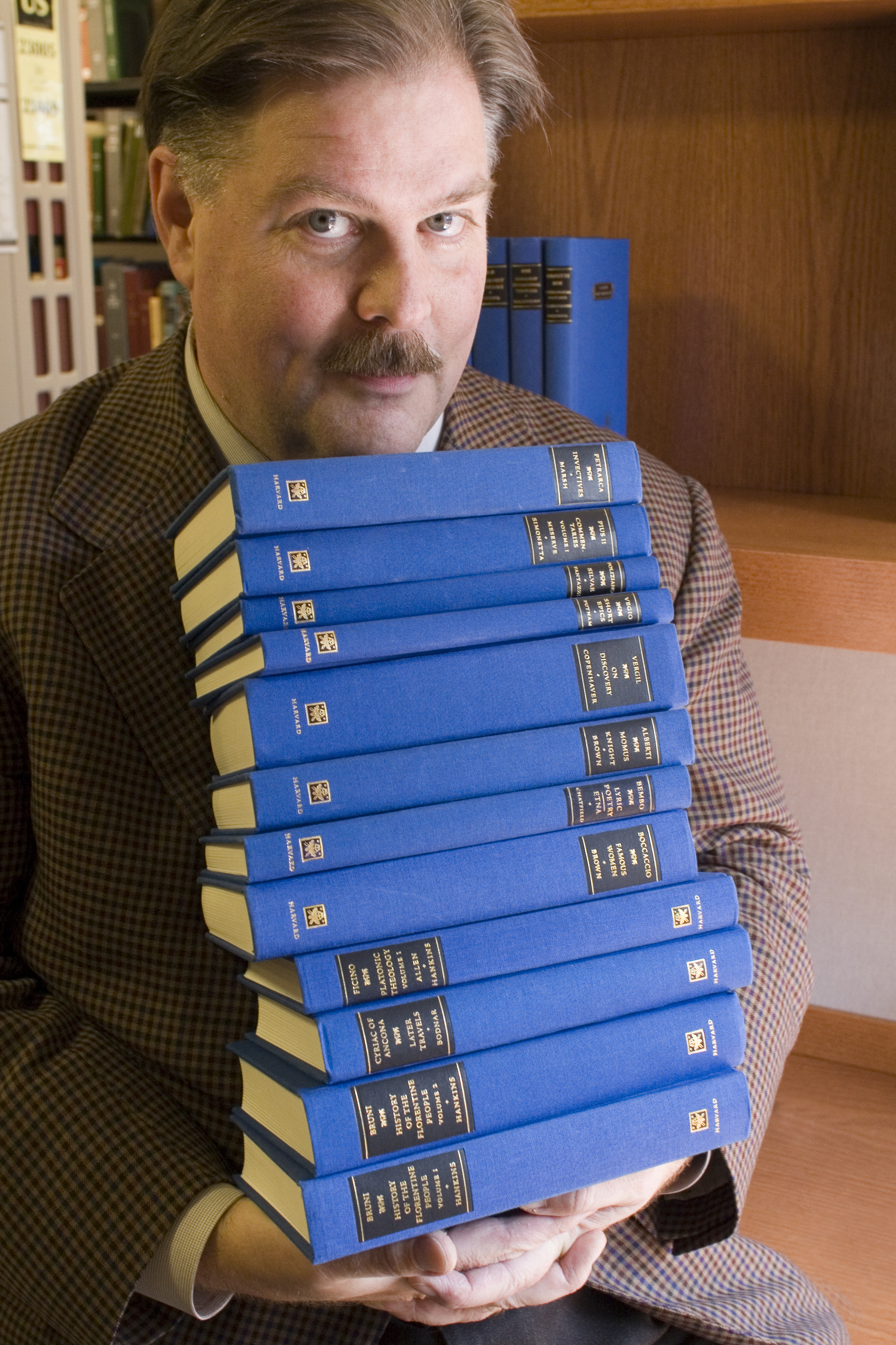 Professor James Hankins holds a collection of books from the I Tatti Renaissance Library