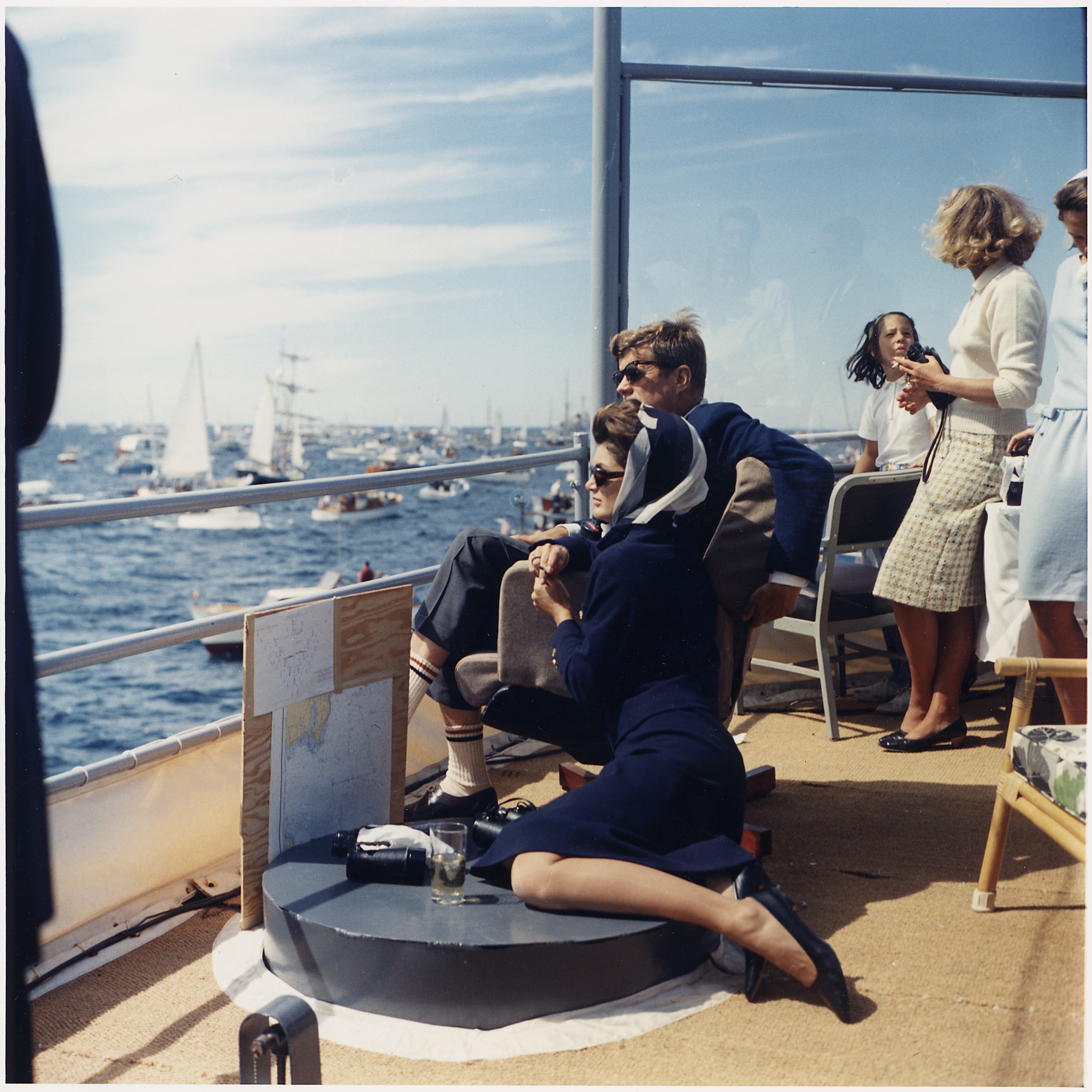 Watching the America's Cup Race. Mrs. Kennedy, President Kennedy, others. Off Newport, RI (<a href="https://en.wikipedia.org/wiki/File:Watching_the_America%27s_Cup_Race._Mrs._Kennedy,_President_Kennedy,_others._Off_Newport,_RI,_aboard_the_USS_Joseph_P...._-_NARA_-_194214.jpg" target="_blank" rel="noreferrer noopener">Public Domain</a>)