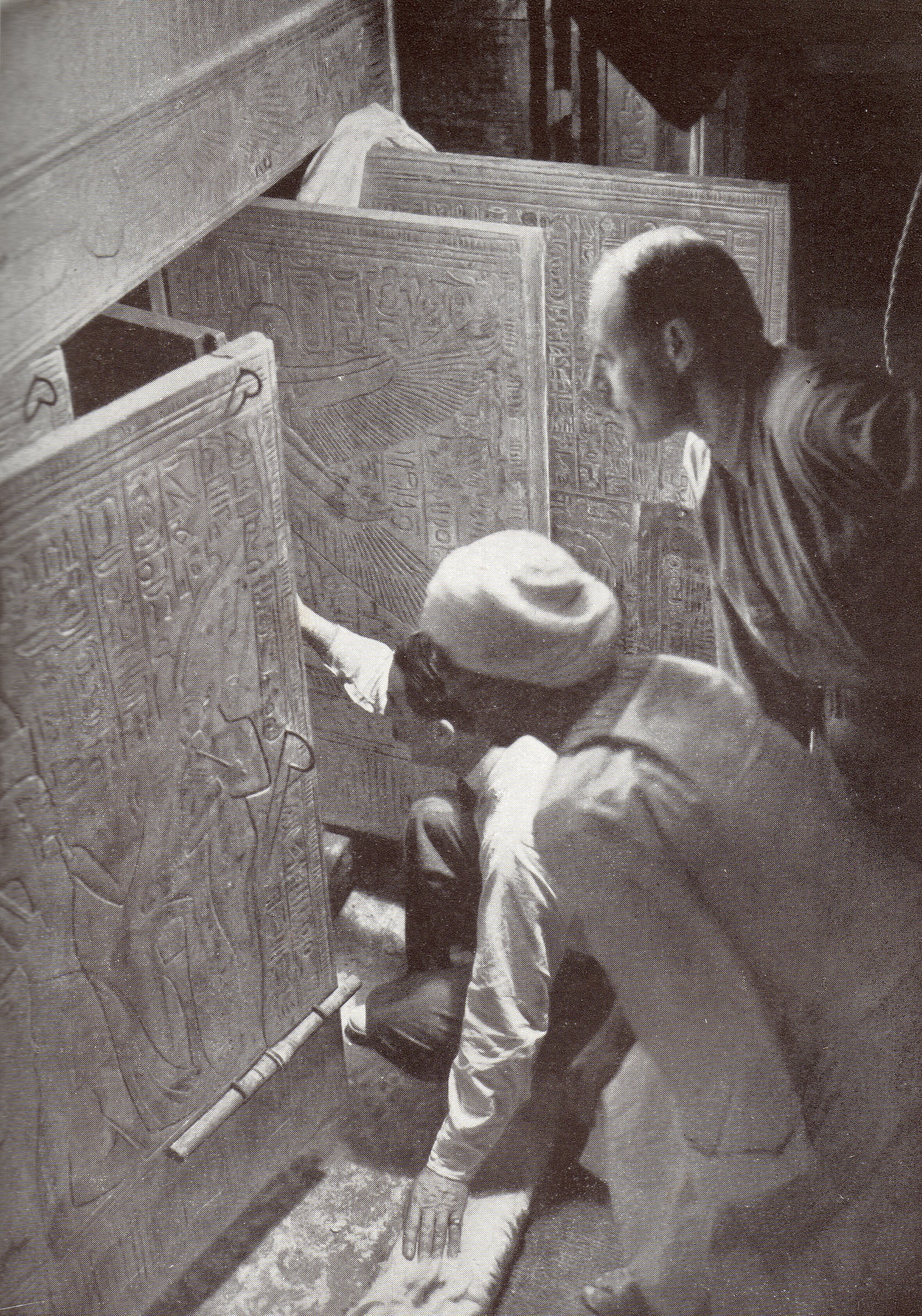 A man opens a decorated door as two other men watch