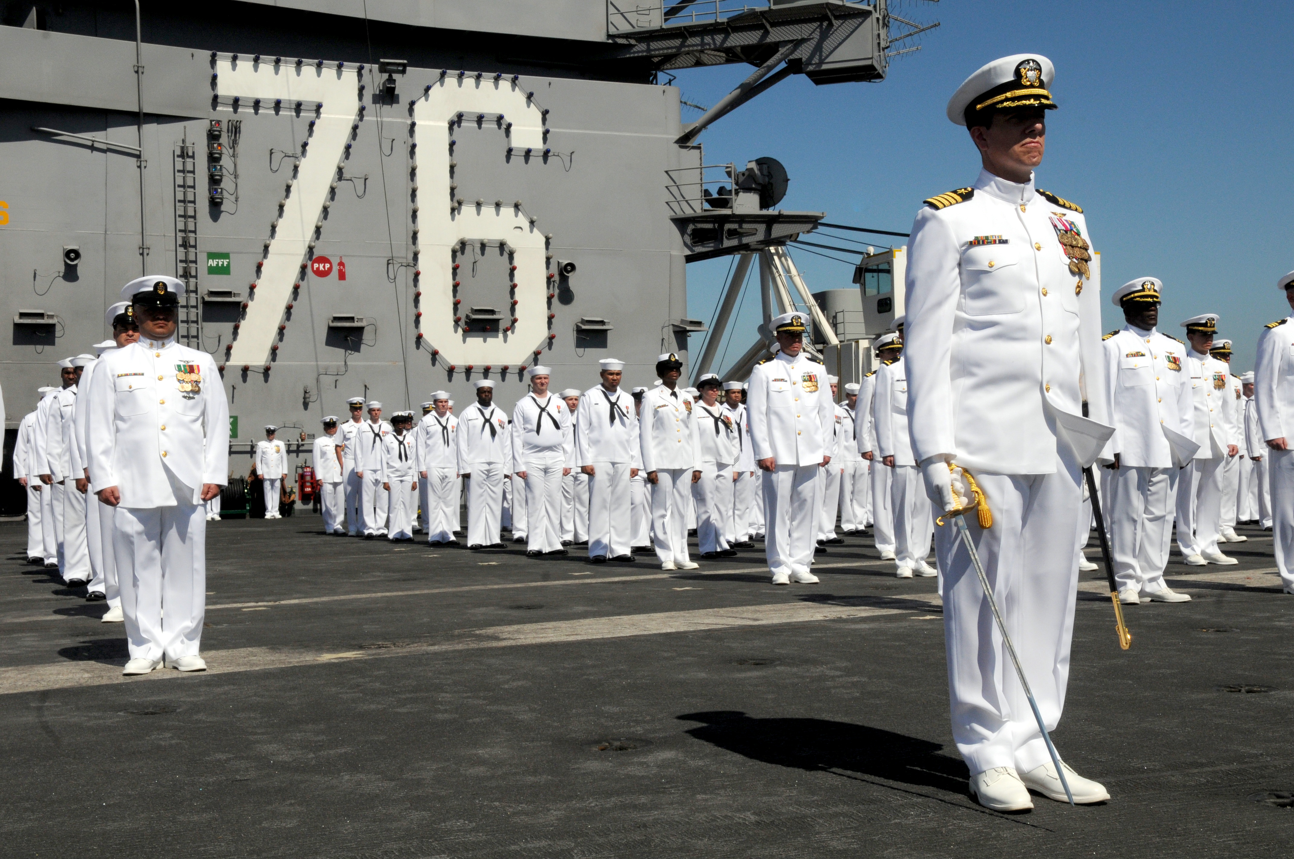 An Indian Navy sailor adjusts his colleague's uniform prior to the