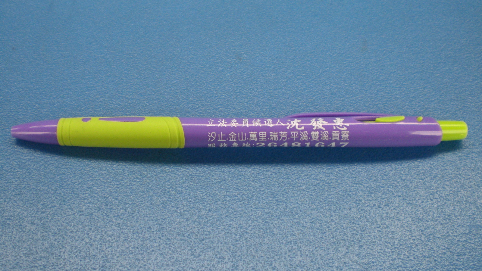 Ugly yellow-green and purple plastic ballpoint pen with white Chinese characters advertising an electoral candidate.