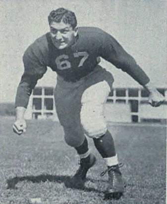 A black and white photo of Pregulman in uniform posing like he is about to block or tackle someone