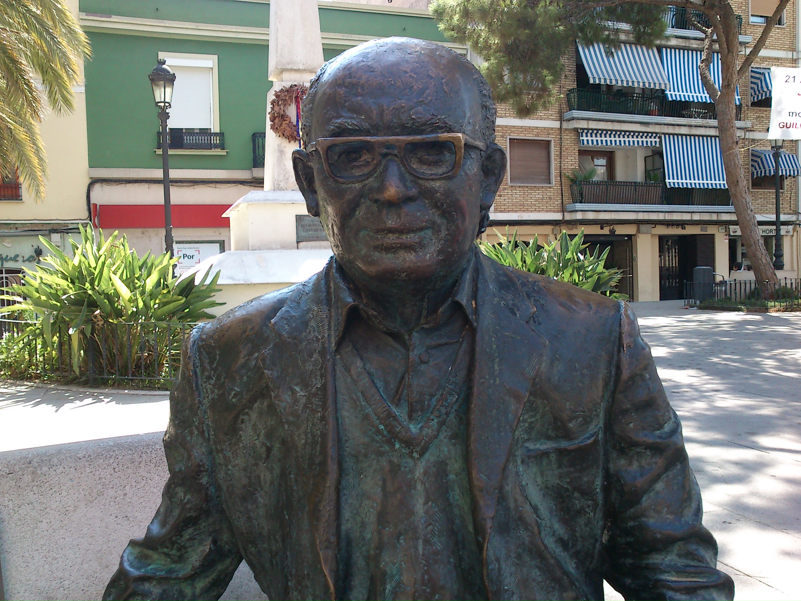 Estatua en bronce del autor sentado en un banco de la plaza Emilio Castelar de Burjasot