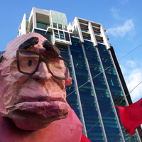 Members of Socialist Alternative assisted in the construction of this effigy of former Prime Minister John Howard, made by the Victorian College of the Arts Student Union. The building in the background is RMIT University, occupied during a demonstration against education cuts in 2005. Pighead.jpg