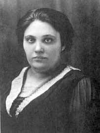 a young woman with dark hair and eyes, wearing dark dress with a lace collar. She is not smiling.