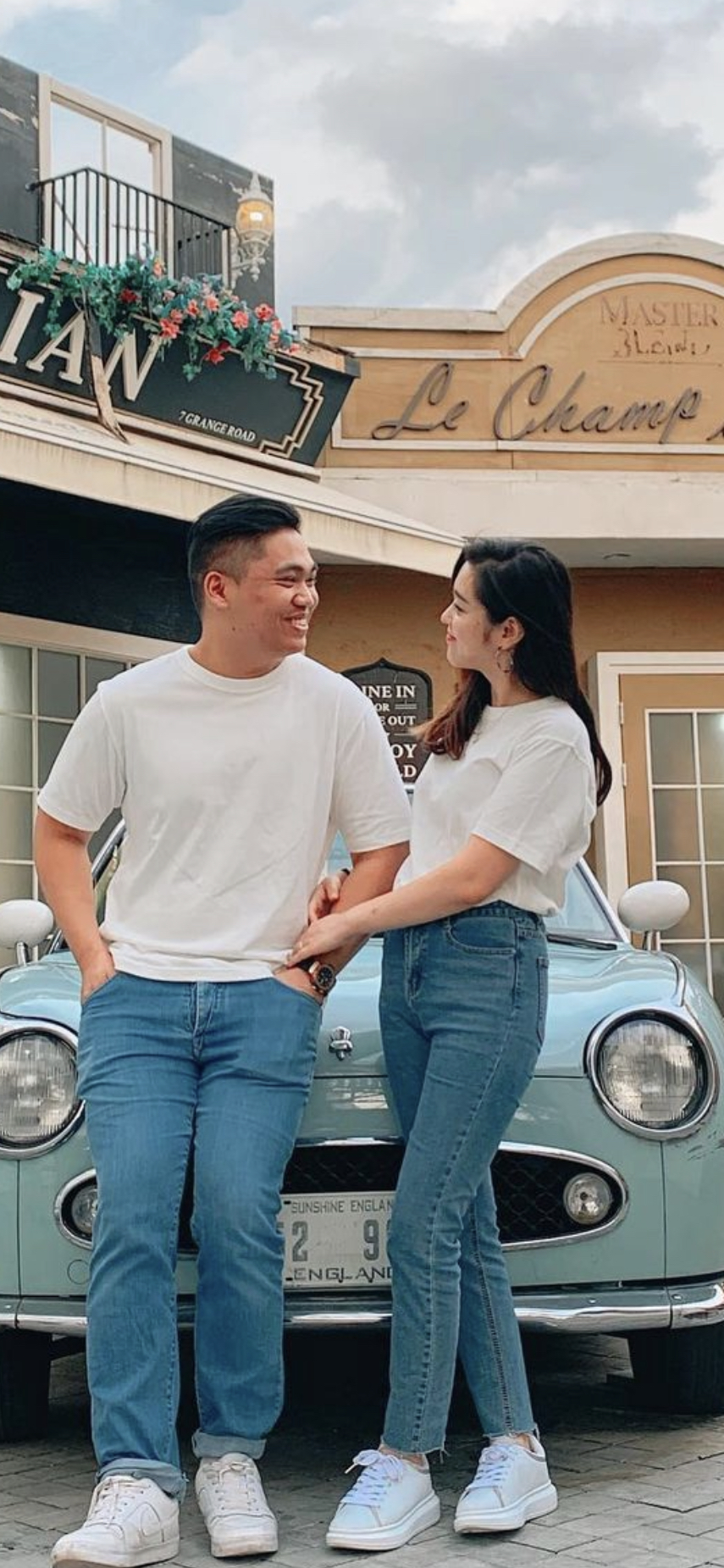 Smiling young couple looking at each other sitting on red car hood Stock  Photo - Alamy