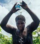 image of a woman pouring water on her head under hot sun.