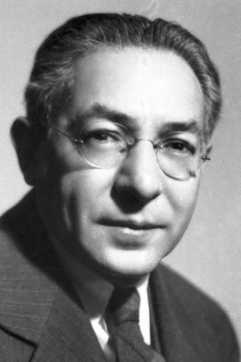Head and shoulders of man in suit and tie wearing glasses