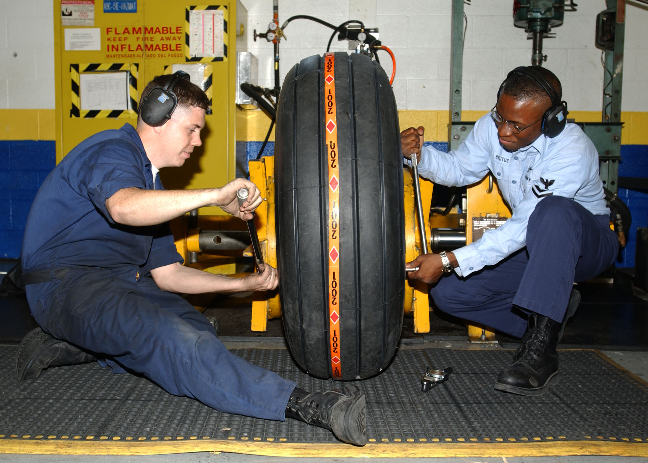 US Navy 030618 N 3970R 003 Aviation Structural Mechanic 3rd Class Nichalos Baldwin and Aviation Structural Mechanic 2nd Class Eddie Brutus work together to properly torque the fittings on an aircraft tire