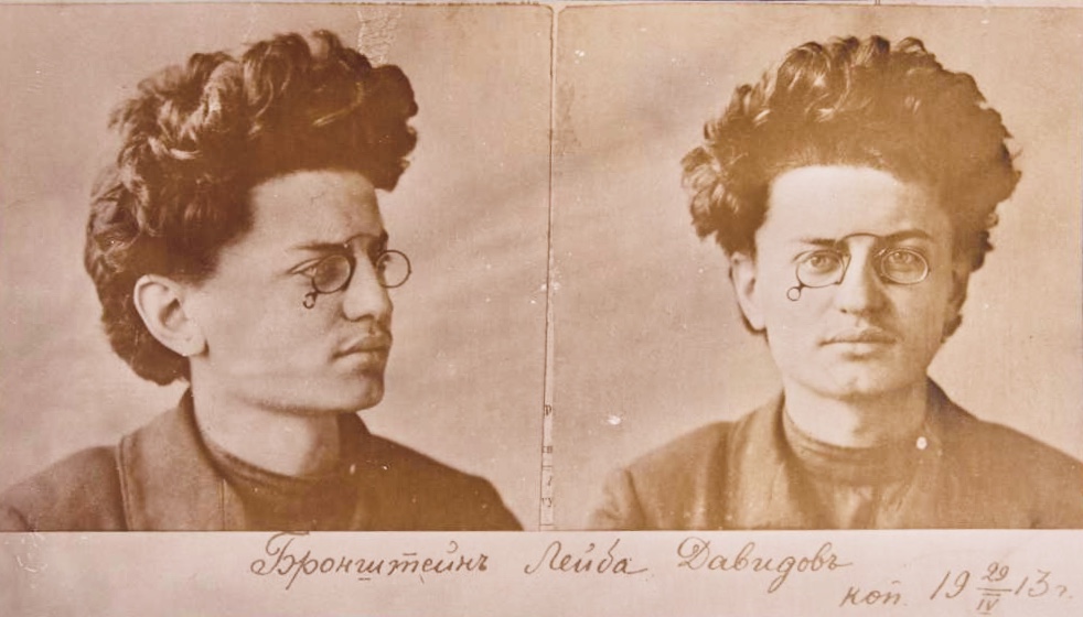 Two early 20th century mugshots of a man with voluminous hair.