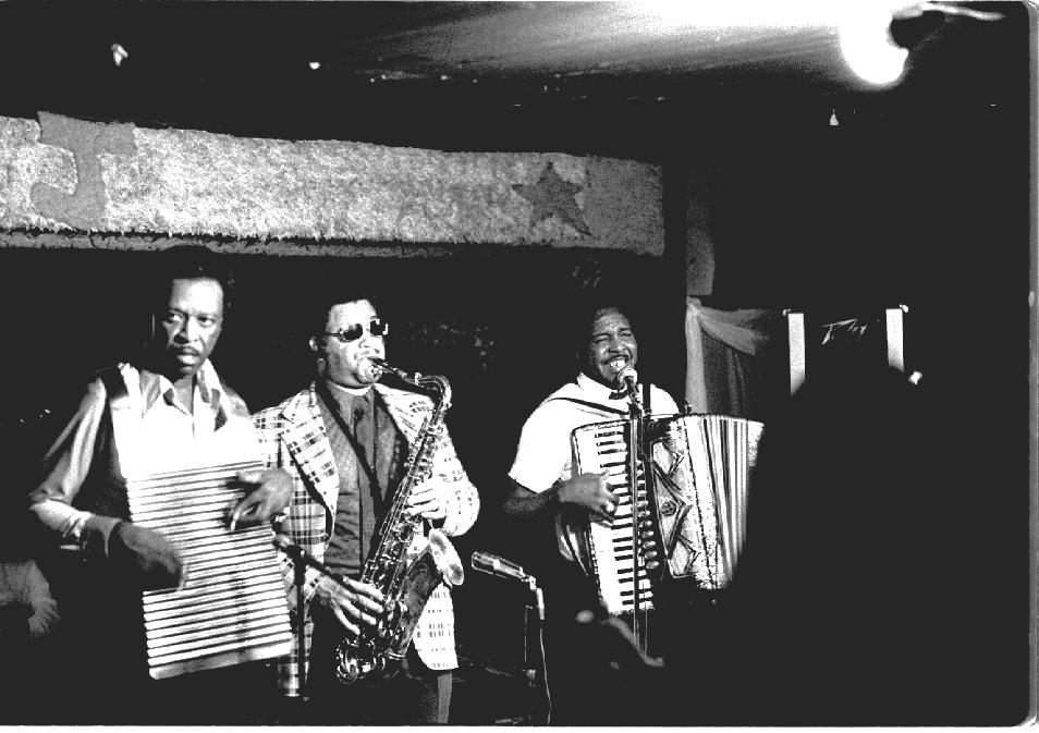 Chenier Brothers performing at Jay's Lounge and Cockpit, [[Cankton, Louisiana]], Mardi Gras, 1975<br>Clifton Chenier on accordion, brother Cleveland on washboard and John Hart on tenor saxophone.