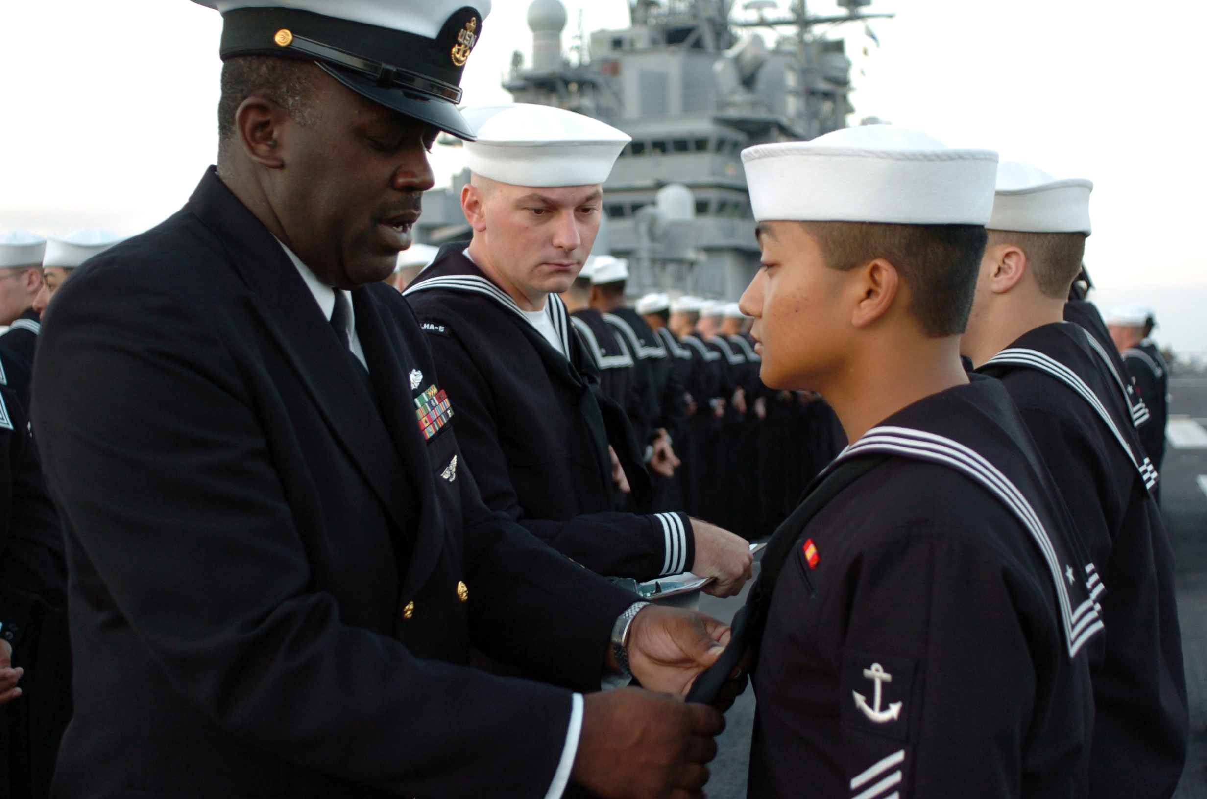 US_Navy_051003-N-9866B-004_Chief_Boatswain%27s_Mate_Keith_Oliver%2C_left%2C_evaluates_his_Sailors_during_a_Service_Dress_Blues_uniform_inspection.jpg