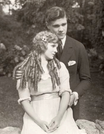Mary Miles Minter (playing Anne Shirley) snuggles with Paul Kelly (Gilbert Blythe) in a scene still for the 1919 silent film Anne of Green Gables