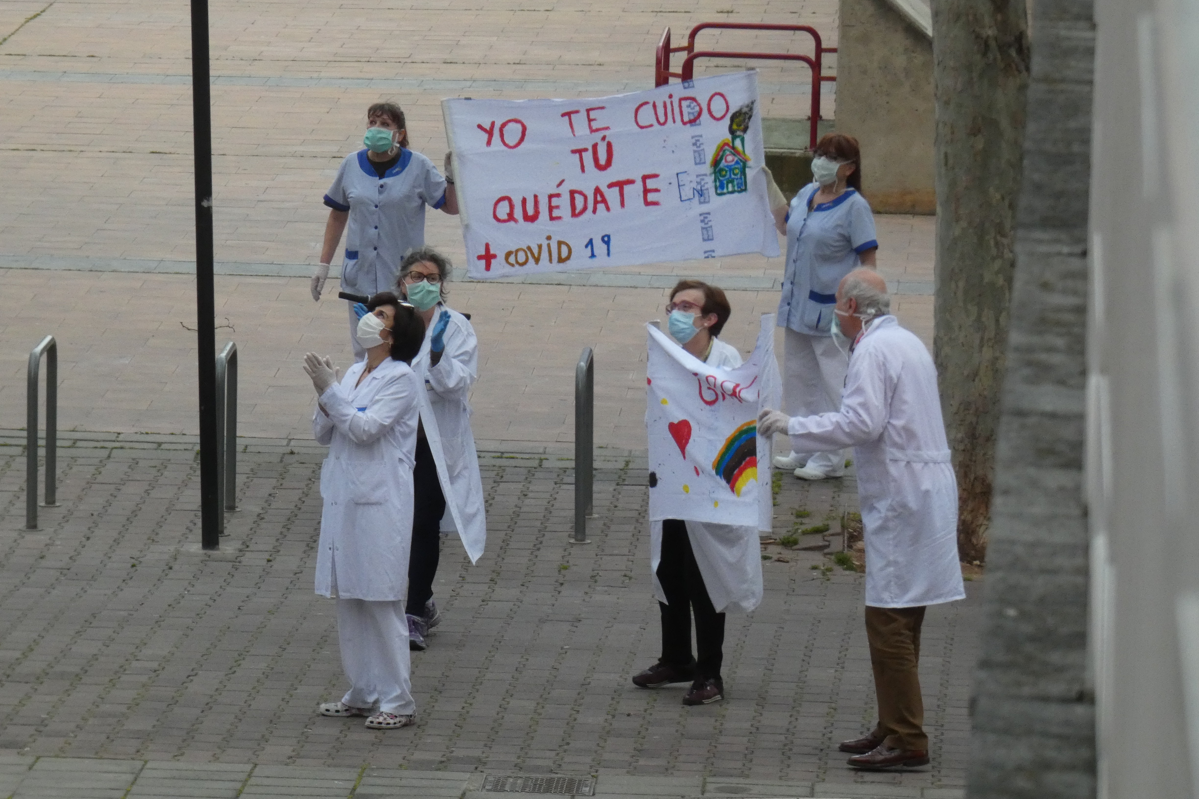 Sanitarios en la calle animando con un cartel que dice "Yo te cuido, tú quédate"