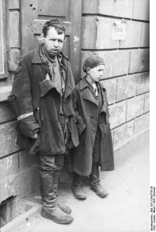 Polen, Warschauer Ghetto.- ärmlich gekleideter Mann und Junge an Hauswand, 21.Juni 1941