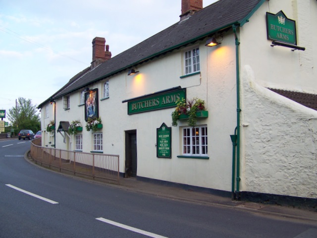 An image of the Butcher's Arms inn in Carhampton, a white building with green signage.