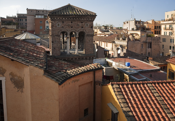 Campanário românico rodeado por outros edifícios.