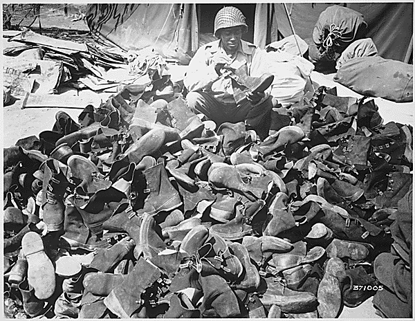 File:"Pfc. Robert Askew...with the 3278th Quartermaster Company, examines overshoes which have been turned in. Overshoes proved their worth and helped prevent trench foot during the rains." - NARA - 531412.gif
