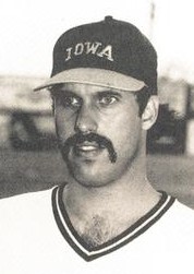 Un jugador de béisbol con una camiseta blanca y una gorra oscura.