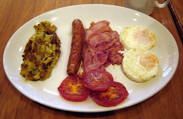 Full English breakfast with bubble and squeak, sausage, bacon, grilled tomatoes, and eggs