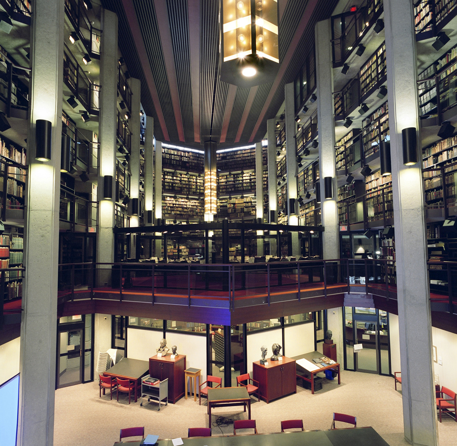 At one of the open atria at the Thomas Fisher Rare Book Library, a seminar room is situated at the base under a mezzanine and upper-level shelving.