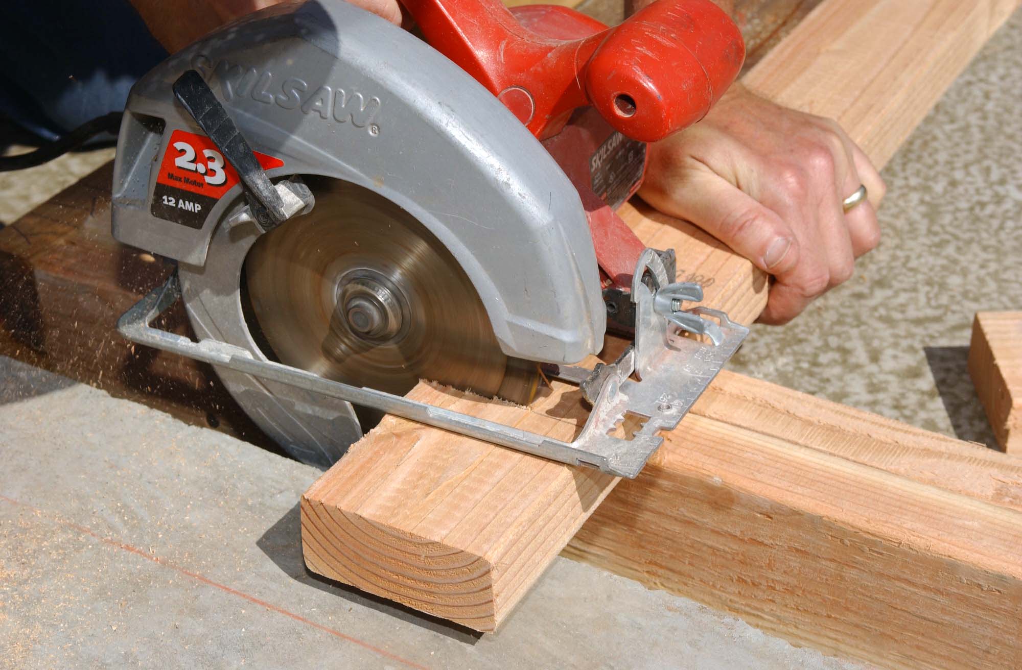 Worker hands details of wood cutter machine with a circular saw and wooden  board. Circular cutting saw in action. Stock Photo