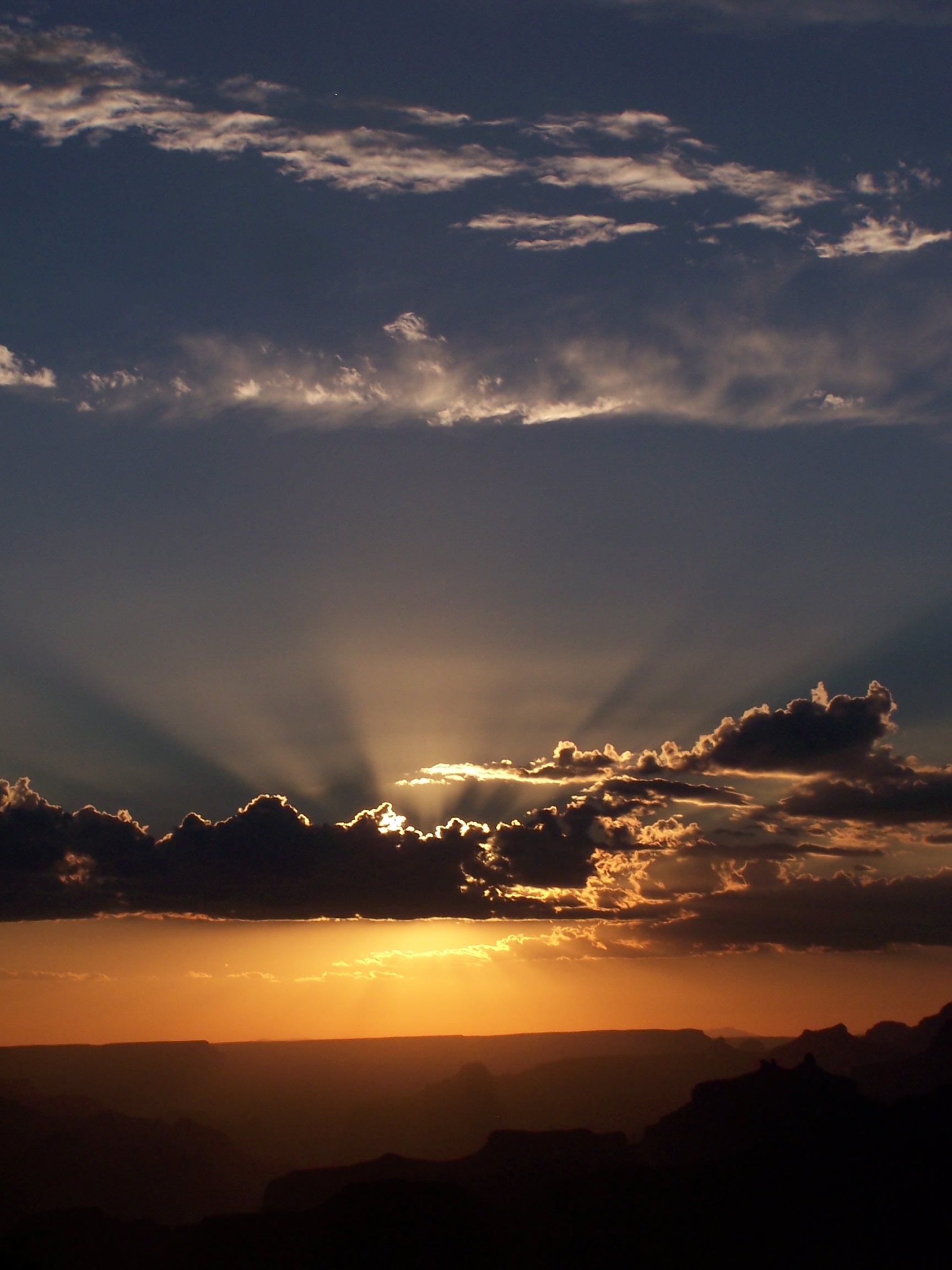 Sun setting while rays of light emit from behind a cloud