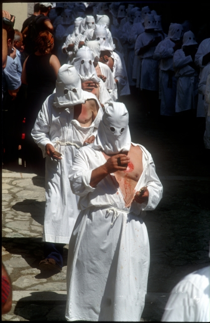 A confraternity of penitents in Italy mortifying the flesh with a spugna, an instrument of penance; capirote are worn by penitents so that attention is not drawn towards themselves as they repent, but rather to God.