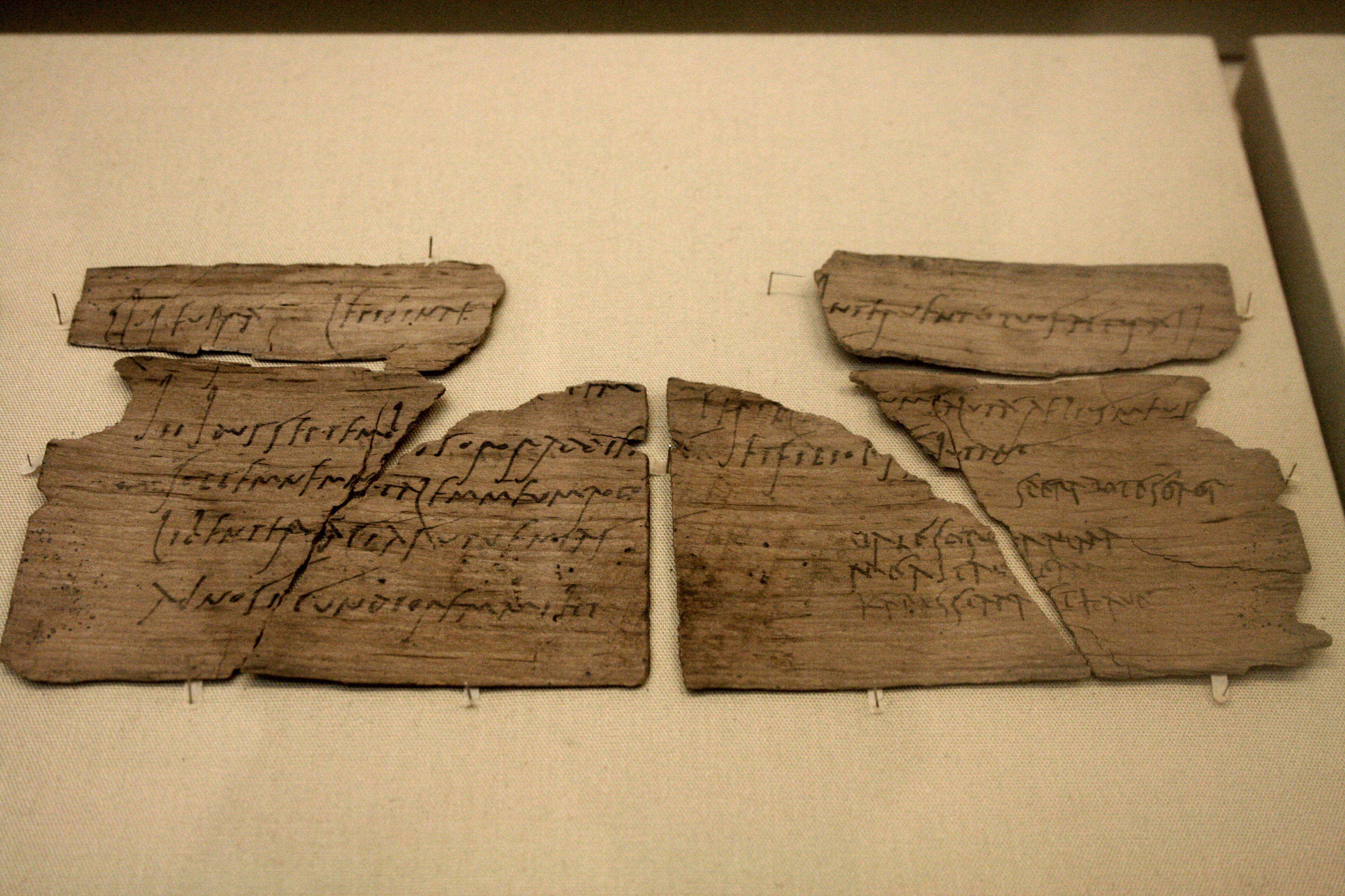 Image of a writing tablet containing a birthday invitation; it is a thin piece of wood covered in writing in black ink and broken into six pieces 