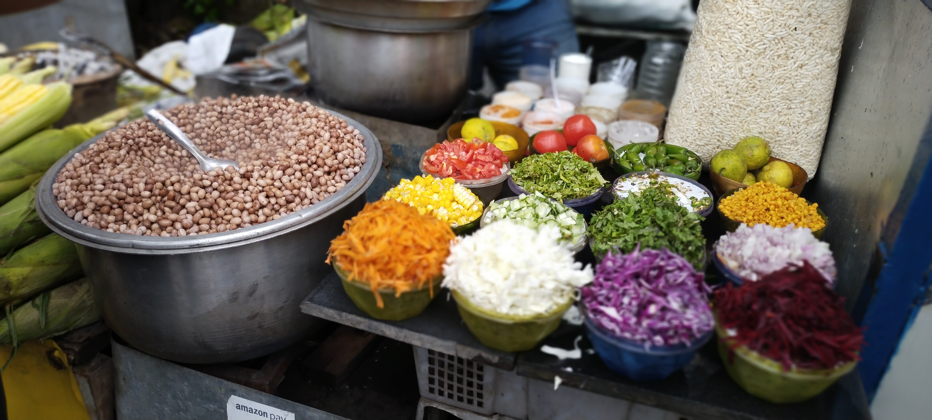 various toppings for street food in bowls next to a large pot of cooked peanuts