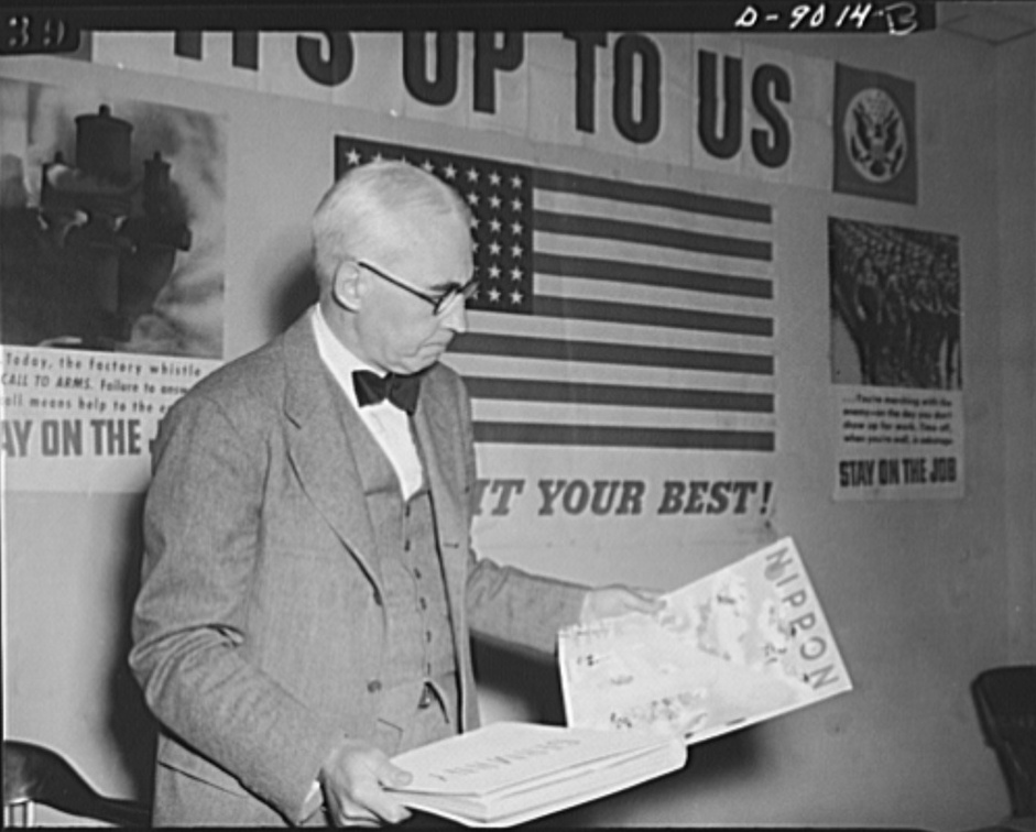 Elmer Davis, Director of the Office of War Information, examines Nazi and Japanese propaganda organs at a press conference that explained how the OWI was fighting the propaganda war (March 6, 1943).