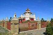 Overview of the monastery complex with white stupas on the fence, pagodas in the courtyard, and the monastery in the center