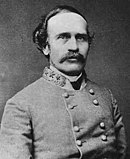 Black and white photo shows a man with a moustache and receding hairline. He wears a gray military uniform with three stars on the collar.