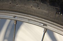 Aluminium rim worn out by V-brakes. The outer wall has been worn through and the wheel is dangerously weakened. This is a disadvantage of rim brakes. Bicycle rim - worn out.jpg
