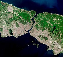 Image satellite montrant une mince parcelle de terre, densément peuplée au sud, coupée en deux par une voie navigable