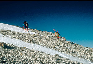 U.S. Geological Survey climbing party reaching the east rim of the summit caldera on Mount Churchill. Blocky debris in the photo consists of pumice and lithic fragments ejected 1,250 years ago, during the eruption which formed the eastern lobe of the White River Ash.