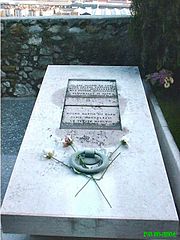 Photo couleur de pierre tombale avec inscription, gros anneau de bronze et trois roses.