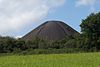 Kerucut besar hitam gundukan dengan pohon-pohon di latar depan